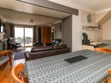 A dining area with a table and chairs overlooking a living room with sofas and a fireplace at Aberdauddwr in Lampeter