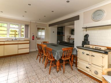 A kitchen with a dining table and chairs a stove and cabinets at Aberdauddwr in Lampeter