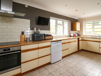 A kitchen with cabinets countertop microwave oven toaster and windows at Aberdauddwr in Lampeter