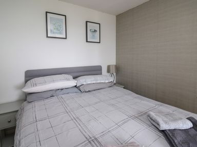 A bedroom with a double bed grey headboard bedside tables with a lamp and two framed pictures on the wall at Aberdauddwr in Lampeter