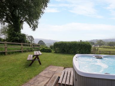 A garden with a wooden bench and a hot tub with bubbling water at Aberdauddwr in Lampeter