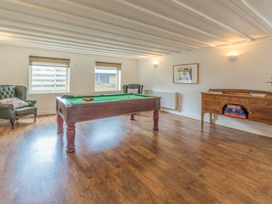 A game room with a pool table two armchairs a wooden sideboard and a framed picture on the wall at Mill House in Lowick