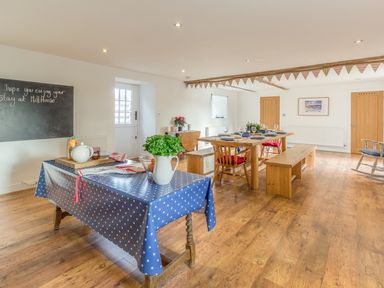 A dining room with wooden table and benches and a smaller table with a blue polka dot tablecloth at Mill House in Lowick