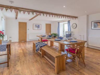 A dining room with a wooden table and benches set with plates and glasses at Mill House in Lowick