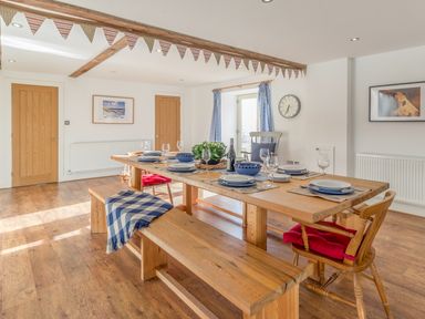 A dining room with wooden table set for meal and wooden benches at Mill House in Lowick