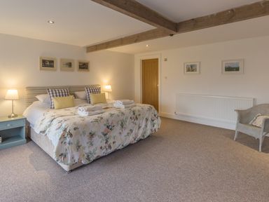 A bedroom with a double bed two bedside tables lamps and a chair at Mill House in Lowick