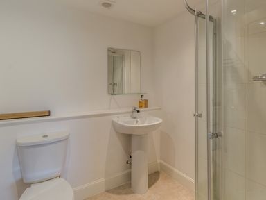 A bathroom with a toilet sink mirror and shower enclosure at Mill House in Lowick