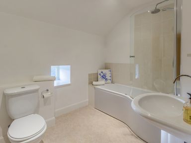 A bathroom with a toilet sink and bathtub with shower at Mill House in Lowick