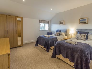 A bedroom with two single beds wooden wardrobe and dresser at Mill House in Lowick