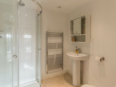 A bathroom with a corner shower enclosure sink with a mirror cabinet and a chrome towel radiator at Mill House in Lowick