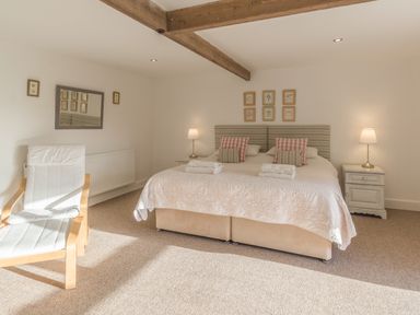 A bedroom with a double bed two bedside tables with lamps a chair and framed pictures on the walls at Mill House in Lowick