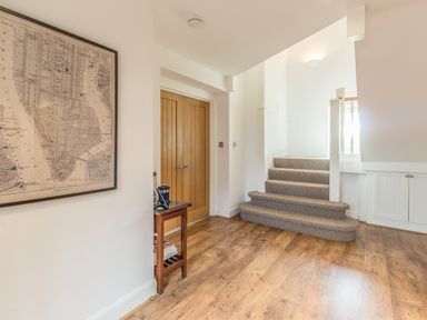 A hallway with wooden flooring a carpeted staircase a wooden table double wooden doors and a framed map on the wall at Mill House in Lowick