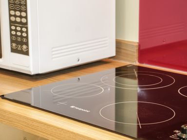 A kitchen countertop with an electric stovetop and a microwave oven at Bryn Y Don Cottage in Benllech