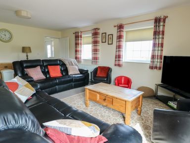 A living room with leather sofas and a wooden coffee table at Ty Ni in Caeathro near Caernarfon