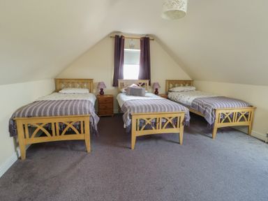 A bedroom with three beds and a window at Ty Ni in Caeathro near Caernarfon