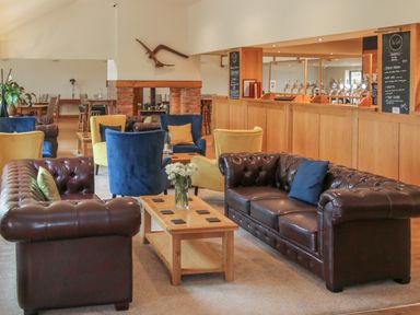 A lounge area with leather sofas armchairs and a wooden coffee table at Callow Lodge 5 Beaconsfield Holiday Park