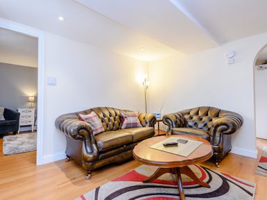 A living room with two leather sofas a wooden coffee table and a patterned rug at Mermaid Cottage in Whitby