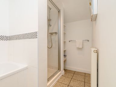 A bathroom with a shower enclosure bathtub towel rail and radiator at Mermaid Cottage Whitby