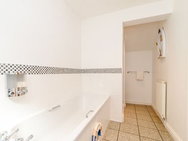 A bathroom with a bathtub and tiled floor at Mermaid Cottage in Whitby