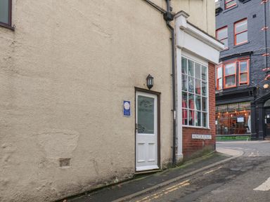 A street corner with a door labeled Ammonite Apartments and a window on Hunter Street at Mermaid Cottage in Whitby