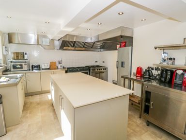 A kitchen with an island countertop ovens a refrigerator and small appliances at Eden Lodge Bardsea