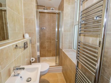 A bathroom with a sink toilet shower and chrome towel radiator at Eden Lodge in Bardsea