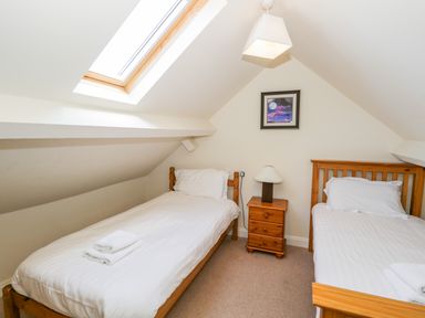 A bedroom with two single beds a bedside table with lamp and a skylight window at Eden Lodge in Bardsea