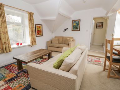 A sitting area with two sofas a wooden coffee table and framed paintings on the wall at Eden Lodge in Bardsea