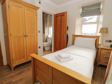 A bedroom with a single bed wardrobe bedside table and an open door to a bathroom at Eden Lodge Bardsea