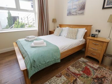A bedroom with a wooden double bed side tables lamps and a patchwork rug at Eden Lodge in Bardsea