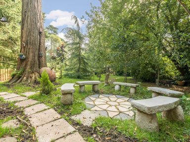 An outdoor garden area with stone benches arranged in a circle around a stone pattern on the ground at Eden Lodge in Bardsea