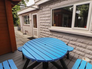 An outdoor area with a blue circular table and a stone pathway at Eden Lodge in Bardsea