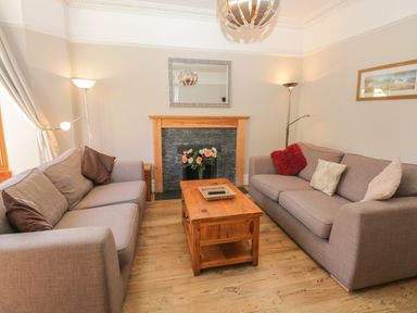 A living room with two sofas a wooden coffee table a fireplace with flowers and lamps at 48 Oak Street in Windermere