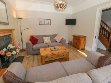 A living room with two sofas a wooden coffee table a floor lamp and a small wooden cabinet at 48 Oak Street Windermere