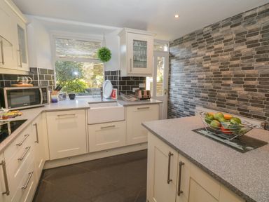 A kitchen with white cabinets a microwave a sink a toaster and a fruit bowl at 48 Oak Street in Windermere