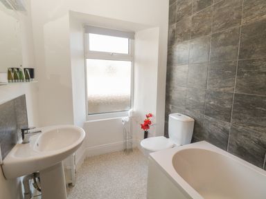 A bathroom with a white sink a toilet and a bathtub with tiled walls at 48 Oak Street in Windermere