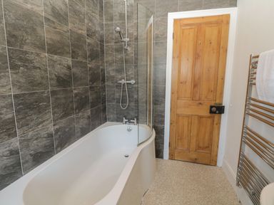 A bathroom with a bathtub shower combination a wooden door and a chrome towel rack at 48 Oak Street in Windermere