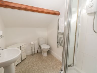 A bathroom with a pedestal sink toilet storage cabinets and a corner shower at 48 Oak Street in Windermere