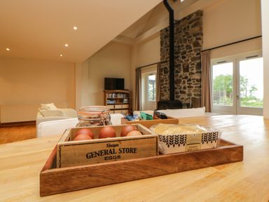 A kitchen table with eggs, lemon biscuits, and tea bags with a living room and stone fireplace in the background at Meader Barn in Peter Tavy near Tavistock