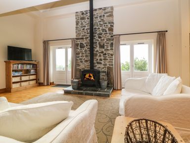 A living room with a stone fireplace flanked by two doors and white sofas with cushions at Meader Barn Peter Tavy near Tavistock