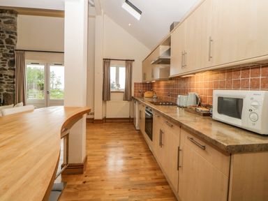 A kitchen with wooden floor cabinets appliances and a curved wooden countertop at Meader Barn Peter Tavy near Tavistock