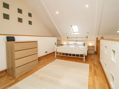 A bedroom with a bed a wooden chest of drawers a rug and skylight windows at Meader Barn in Peter Tavy near Tavistock