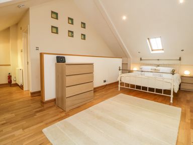 A bedroom with a bed and two nightstands with lamps a chest of drawers and six small square wall decorations at Meader Barn in Peter Tavy near Tavistock