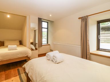 A bedroom with two beds and rolled towels on one bed at Meader Barn in Peter Tavy near Tavistock