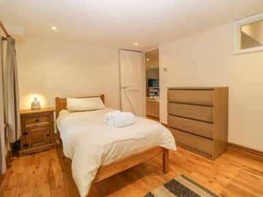 A bedroom with a single bed wooden nightstand and chest of drawers at Meader Barn in Peter Tavy near Tavistock