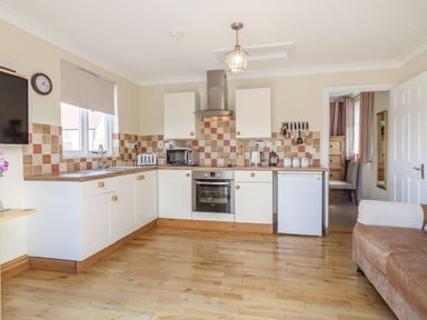 A kitchen with white cabinets wooden countertops and tiled backsplash at Norbank Garden Studio in Bressingham