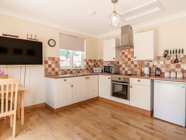 A kitchen with white cabinets wooden countertops and various appliances including a microwave and toaster at Norbank Garden Studio in Bressingham