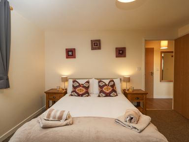 A bedroom with a double bed side tables lamps and rolled towels at Roan Cottage in Royal Wootton Bassett