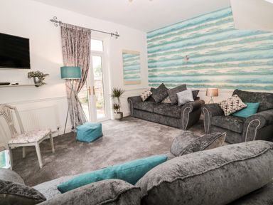 A living room with grey sofas and blue pillows a patterned wall and a floor lamp at St Cuthberts Cottage in Beal near Holy Island
