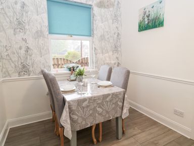 A dining room with a table covered by a tablecloth set for four people with plates and glasses at St Cuthbert's Cottage in Beal near Holy Island